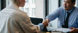Deux personnes autour d'un bureau se serrant la main à la suite d'une négociation annuelle obligatoire