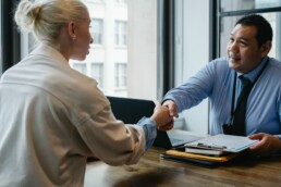 Deux personnes autour d'un bureau se serrant la main à la suite d'une négociation annuelle obligatoire